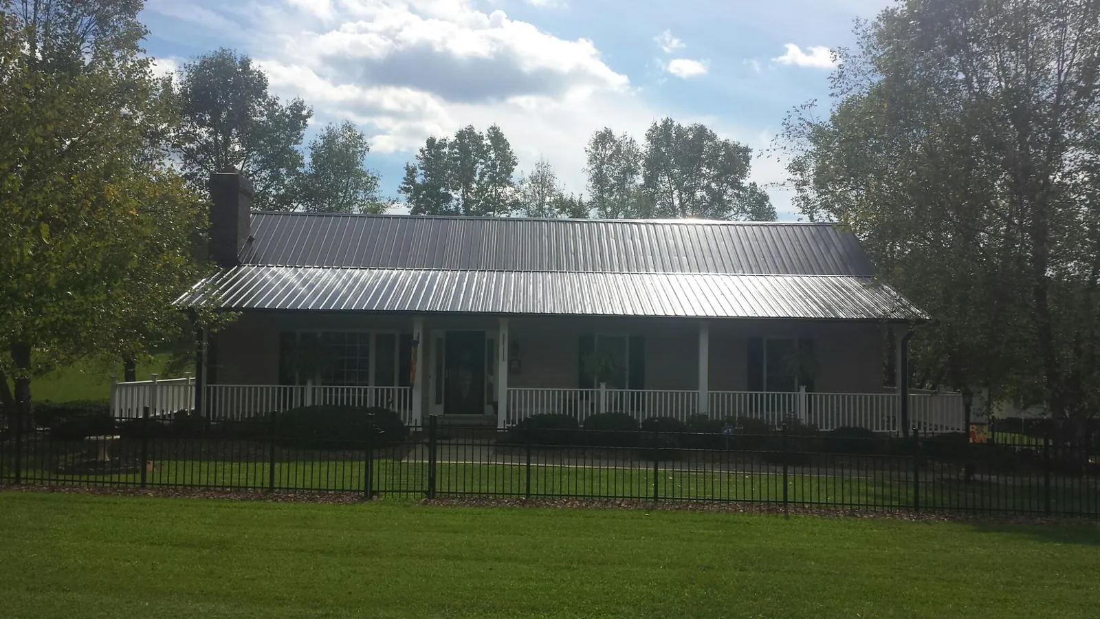 Gray metal roof on a brick ranch with a full width front porch — Gutter Guard Installation work by our crew in Medway