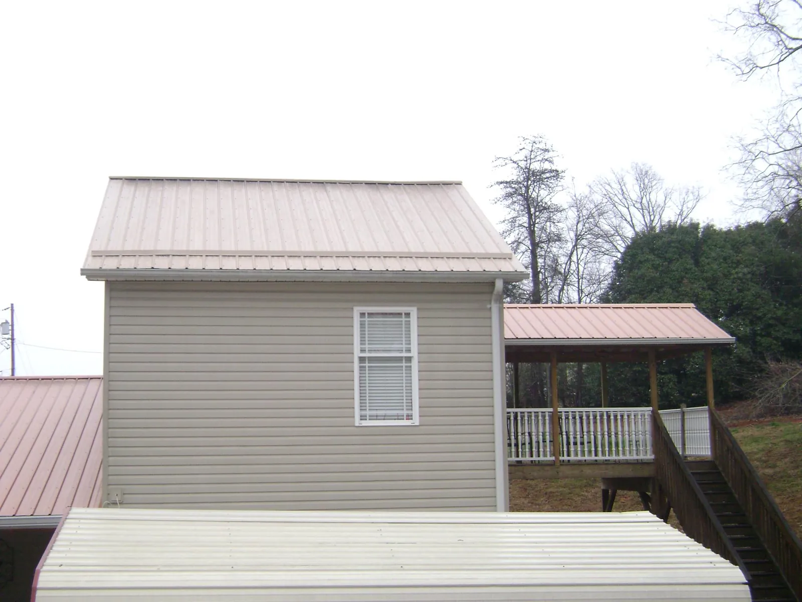Tan metal roofs on a two story addition and attached porch, from a Roof Replacement job in Medway